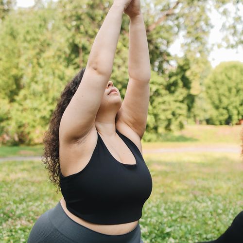 Pleased woman stretching outdoors in a park.